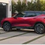 Rear three-quarter view of a red 2026 Chevrolet Blazer with a black roof parked on a residential driveway.