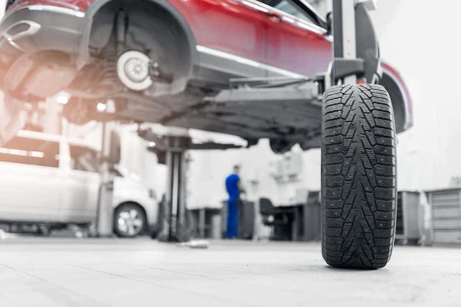 A lifted red car in the middle of a tire rotation in a service center
