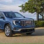 The Luxurious And Dependable 2025 GMC Acadia Denali Trimmed, Blue And Parked Near The Sea