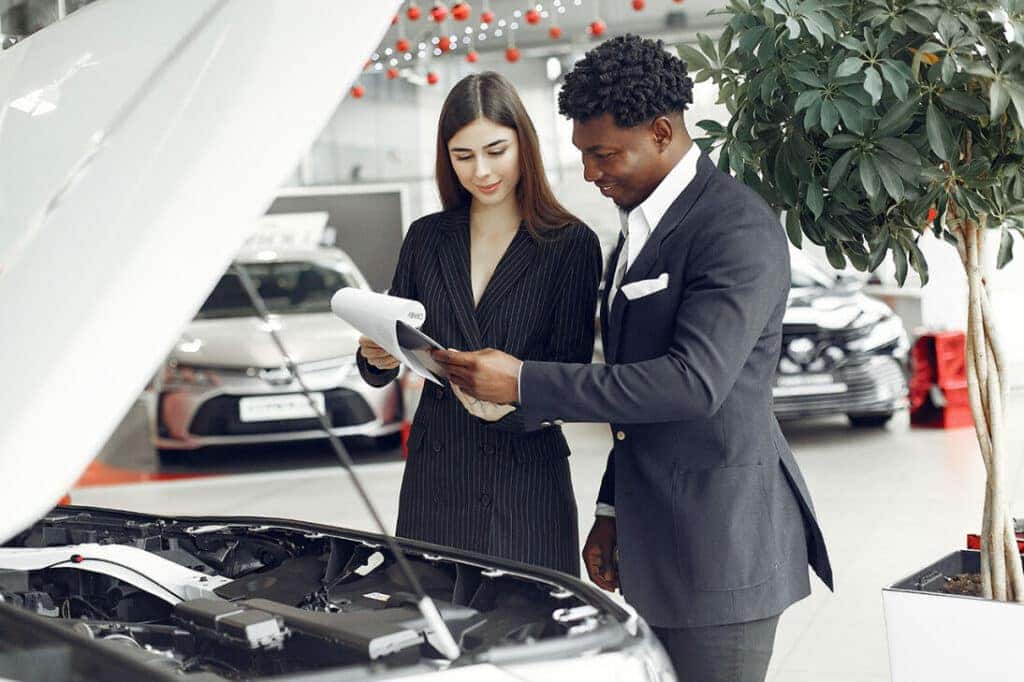 Looking at papers in front of a car