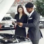Looking at papers in front of a car