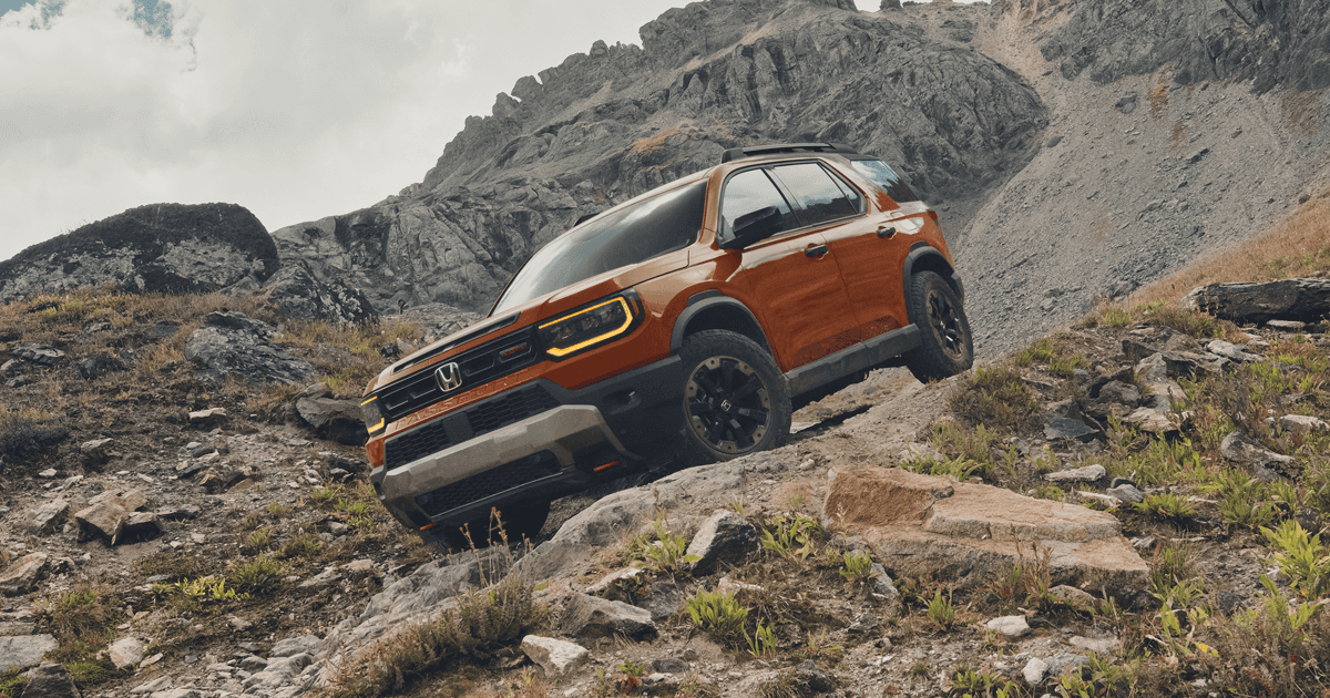 A Honda Passport driving off-road down a rocky hill.