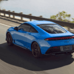 A 2026 Honda Prelude rear view driving on the road next to a lake