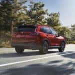 A Honda CR-V in Radiant Red Metallic viewed from behind as it drives past on the road.