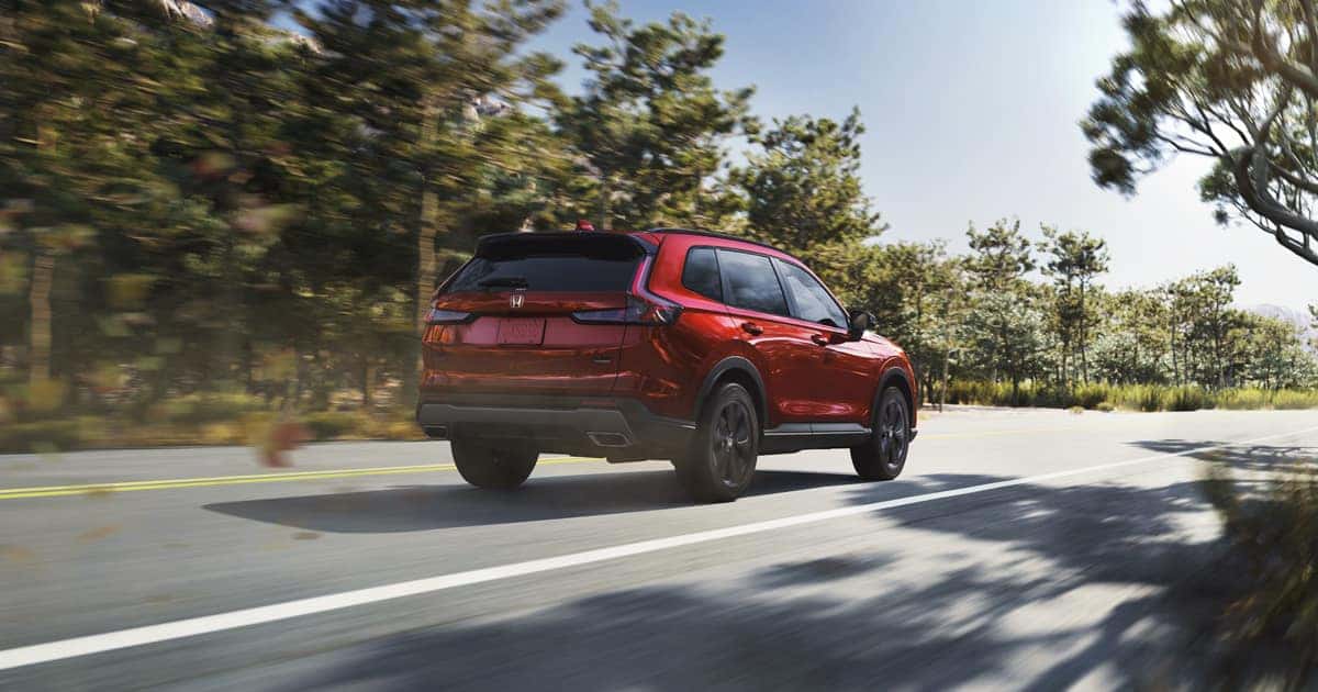 A Honda CR-V in Radiant Red Metallic viewed from behind as it drives past on the road.