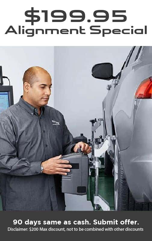A service Technician stands above a car hood.