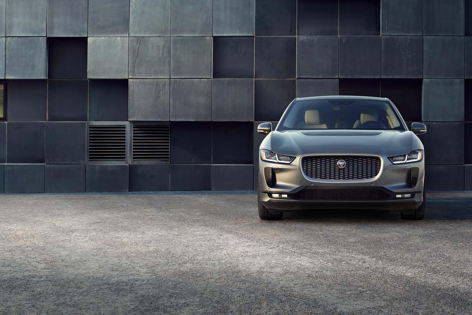 Front view of Jaguar I-PACE parked against a modern tiled wall
