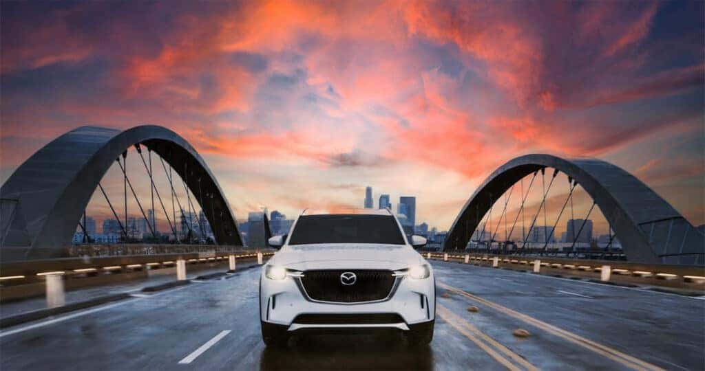 2025-Mazda-CX-90-PHEV-Driving-straight-on-over-a-bridge-at-sunset