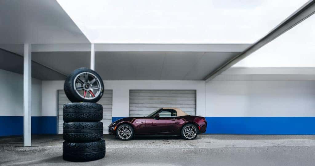 MX-5-Miata-35th-Anniversary-Edition-Parked-By-A-STack-of-Racign-Wheels-and-Tires-in-Front-of-A-Garage