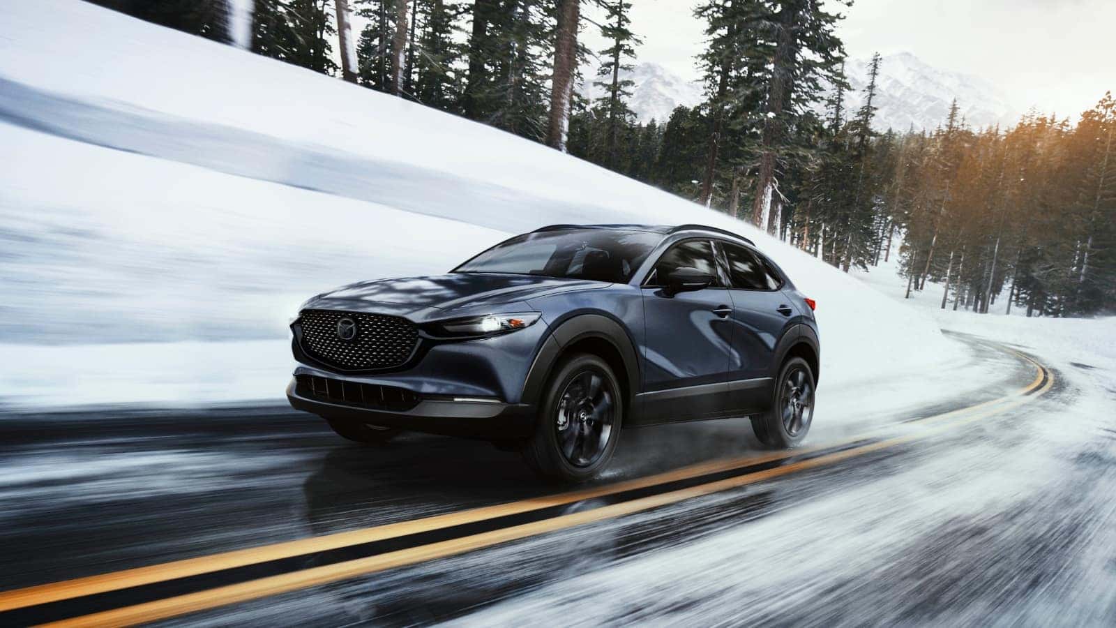 2026 Mazda CX-30 driving on a snowy mountain road, showcasing all-weather capability and confident handling