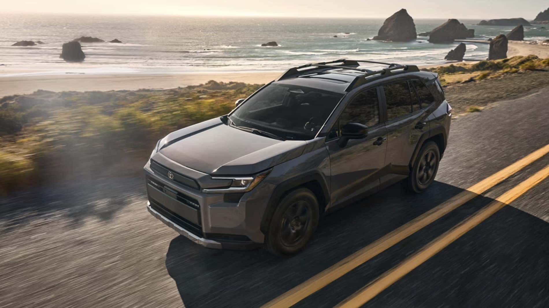 2026 Toyota RAV4 driving along a coastal highway with ocean cliffs and rocky shoreline in the background