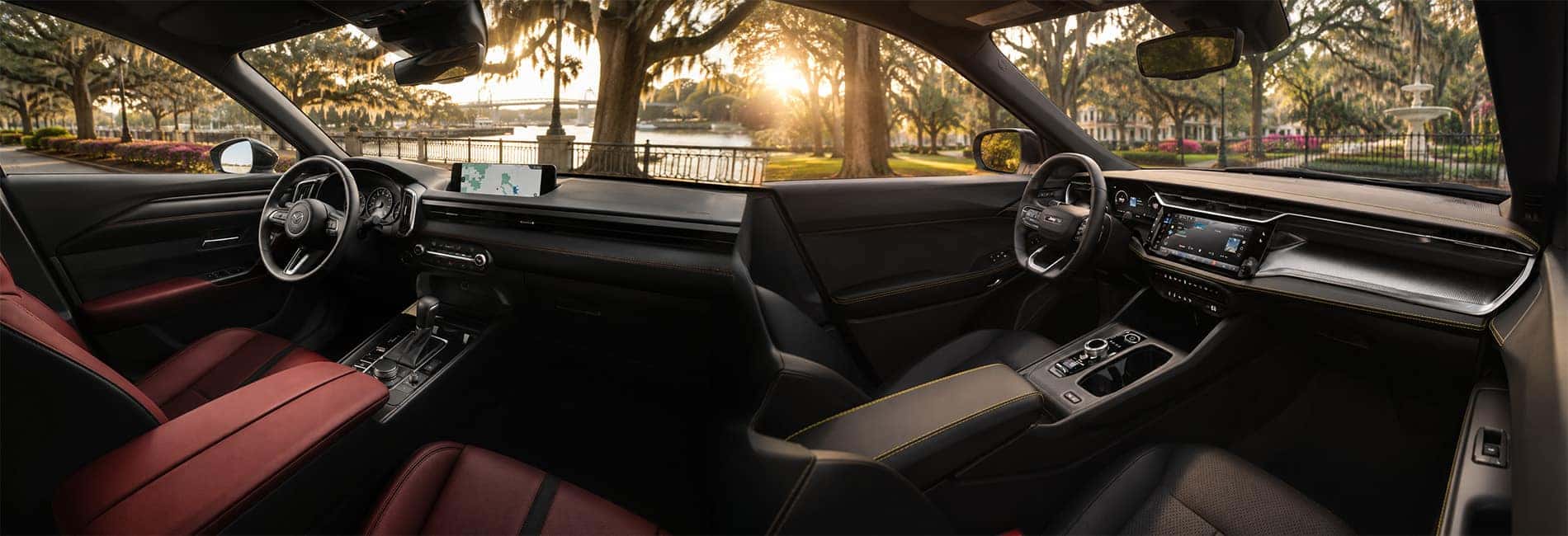 Side-by-side view of Mazda CX-50 and Jeep Cherokee cabins showing dashboard layouts, touchscreen displays, and trim materials.