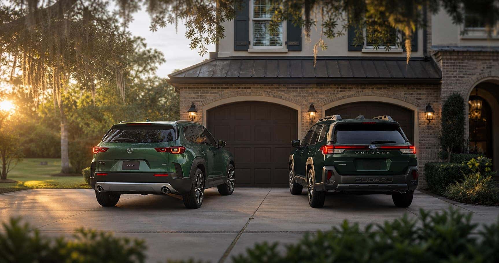 Green Mazda CX‑50 and green Subaru Outback parked side by side in driveway at sunset in front of brick home highlighting rear styling and design differences.