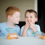 two young boys eating food from the backpack program at home