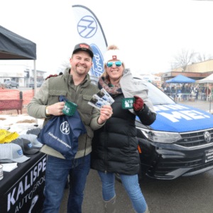 Couple holding raffle tickets in front the Kalispell Auto Group tent at the Frosty Brewfest event