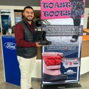 Ford employee holding boots in front of Toasty Tootsies banner