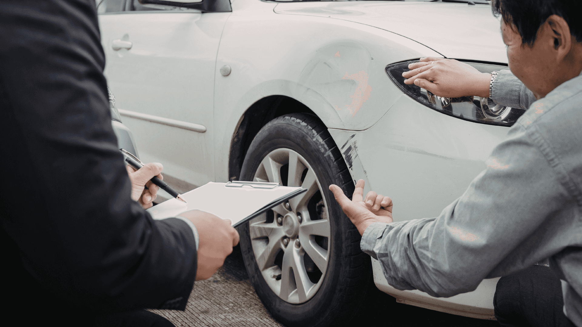 Two people inspecting a vehicle with damage