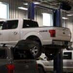 A Ford truck hovering in the sky on a lift in the Kalispell Ford Service department