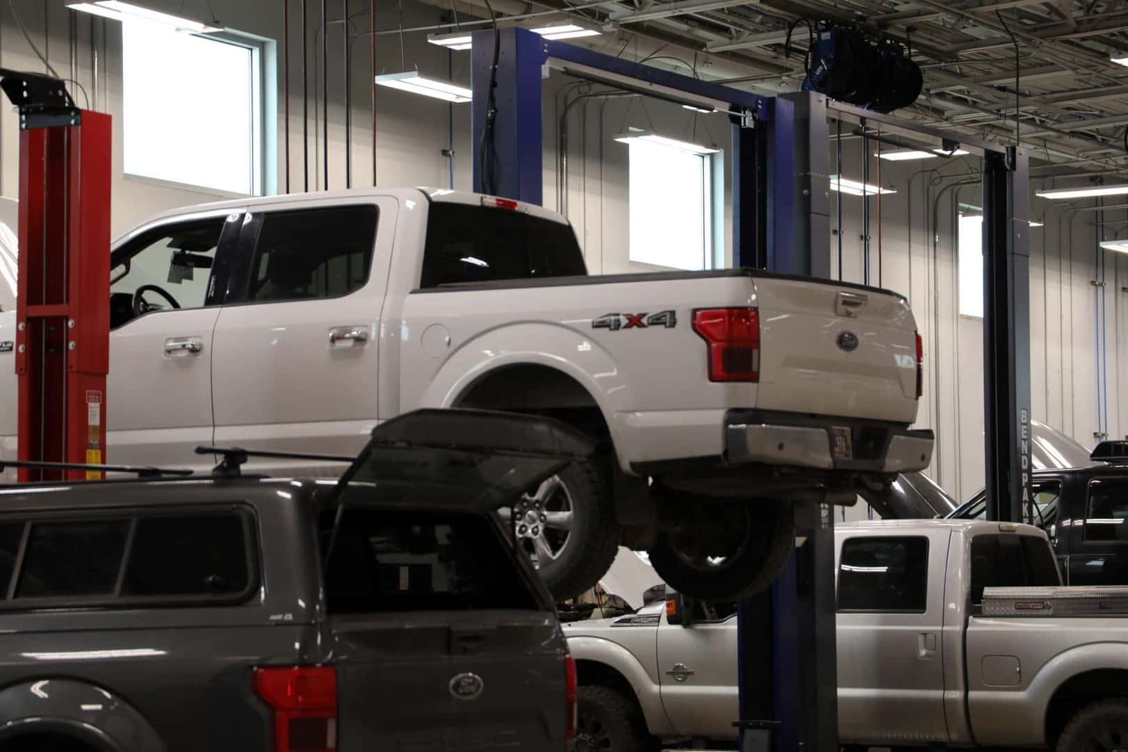 A Ford truck hovering in the sky on a lift in the Kalispell Ford Service department