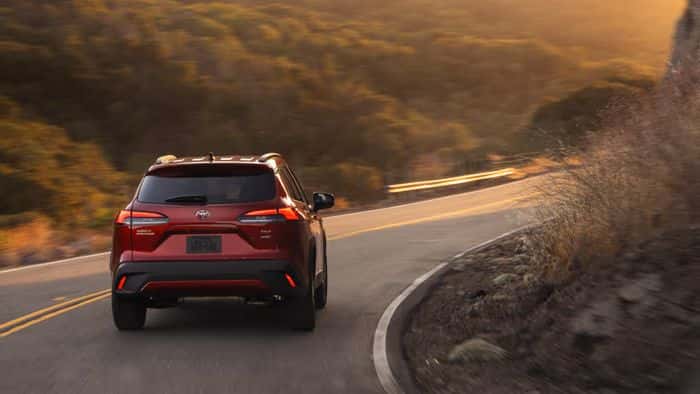Red Toyota Corolla Cross driving on some backroads