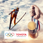 Skiier flying through sky with a hand holding medals