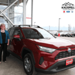 Raaffle ticket winner in front of Toyot dealership with a red Toyota Rav4 next to her