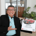 Product specialist holding a try before you buy rent a Toyota sign inside dealership