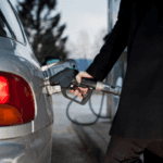 man in black pumping gas into his car