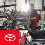 Toyota tech repairing an engine and below performing a oil change