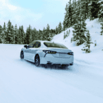 White Toyota Camry driving on a snowy mountain road