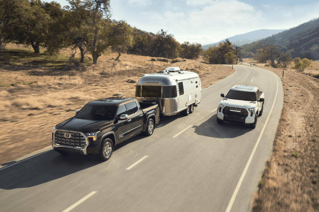 Two Toyota Tundra's on a backroad, one is pulling a camper.