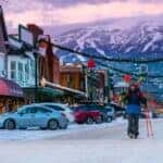 Two skiers walk downtown Whitefish with the Whitefish mountain looming in the background during the cold Montana winter