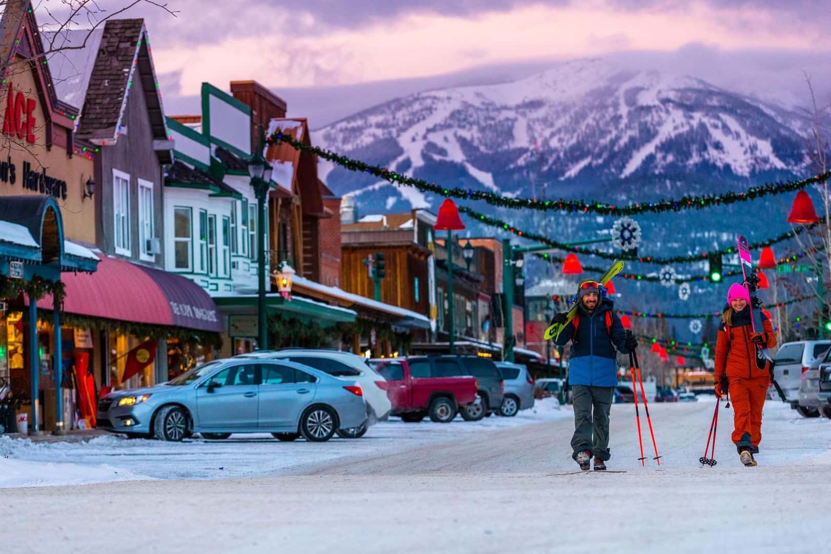 Two skiers walk downtown Whitefish with the Whitefish mountain looming in the background during the cold Montana winter