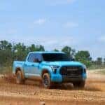 2026 Toyota Tundra TRD Pro in Wave Maker blue driving off-road on a dirt trail.
