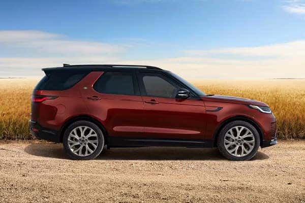 Discovery in burgundy side profile on gravel road through wheat field