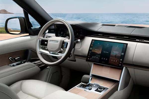 2026 Range Rover luxury interior with large touchscreen, wood trim, and ocean view