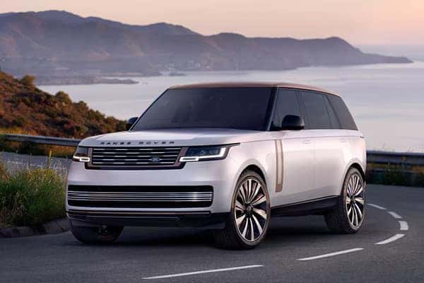 2026 Range Rover in white exterior front three-quarter view on coastal road at sunset