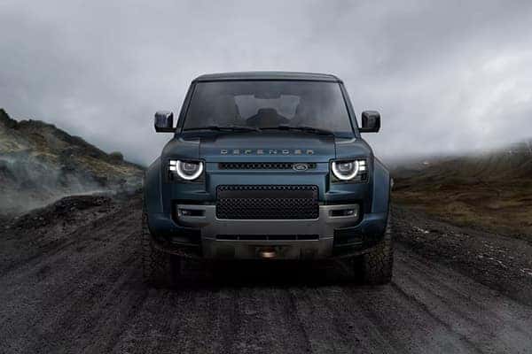 Defender front view on volcanic off-road terrain in dark teal