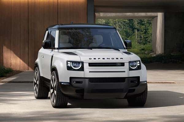 Defender 90 two-door in white parked outside modern home
