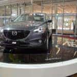 Gray Mazda CX-9 on display in a Mazda dealership showroom.