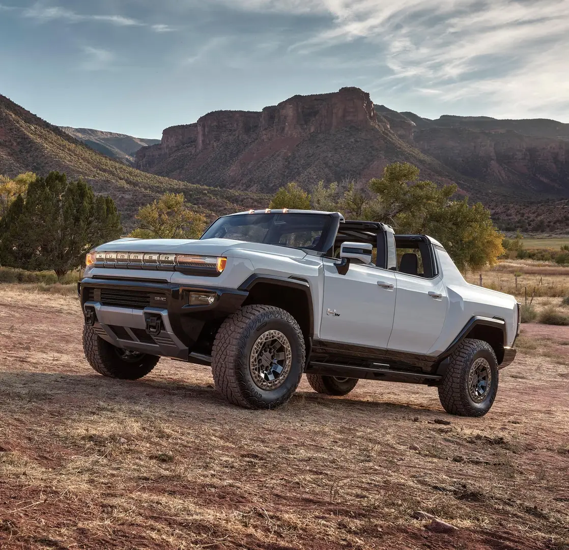 A GMC Hummer H1 parked on a slope at the base of the mountains in the desert.