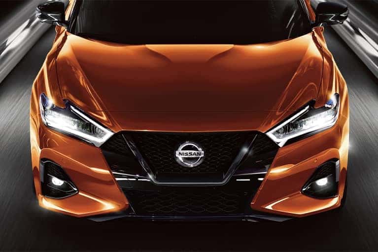 Front angle shot of a 2021 orange Nissan Maxima at night