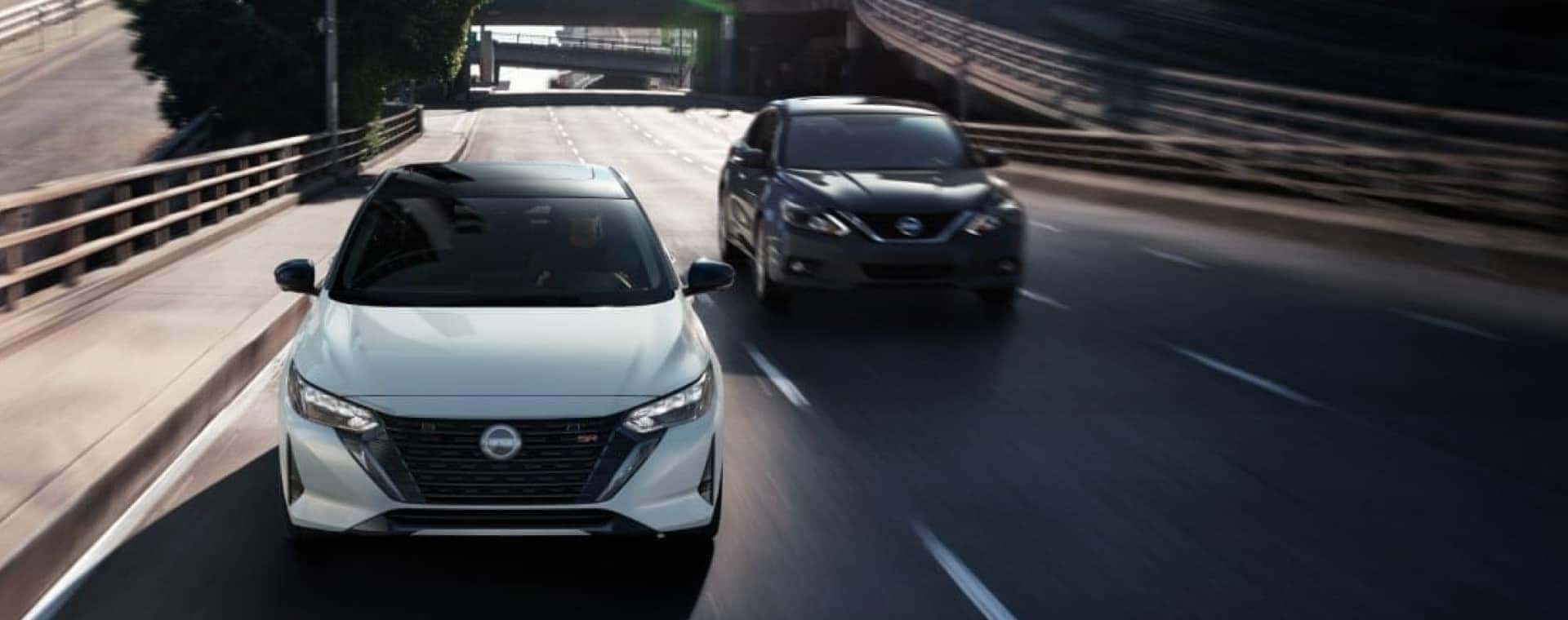 Head-on view of Nissan sedan driving through a city