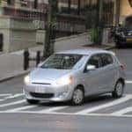 Silver Mitsubishi Mirage driving through a city street.