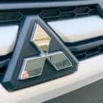 Front grill and logo of white Mitsubishi Outlander.