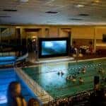 Group of people at an indoor pool with the lights off watching a movie