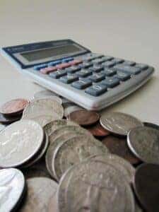 Several coins thrown on a table next to a calculator