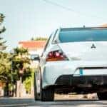 A White Mitsubishi driving away chasing the sun