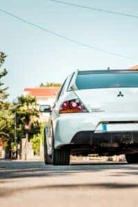 A White Mitsubishi driving away chasing the sun