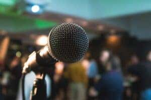 A microphone on a stage in front of people waiting to listen